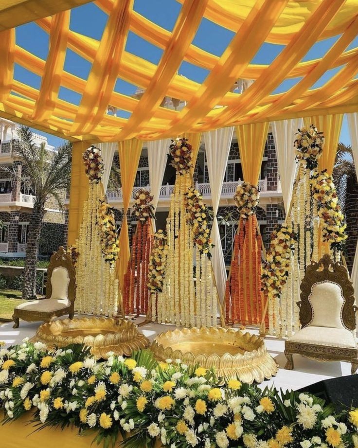 Outdoor Haldi setup with yellow drapes and marigold pillars